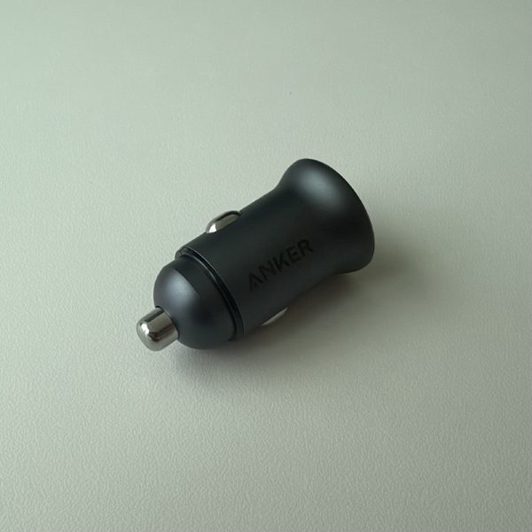 Anker PowerDrive 2 Alloy car charger, a small black metal cylinder with two USB-A ports, sitting on a white surface.