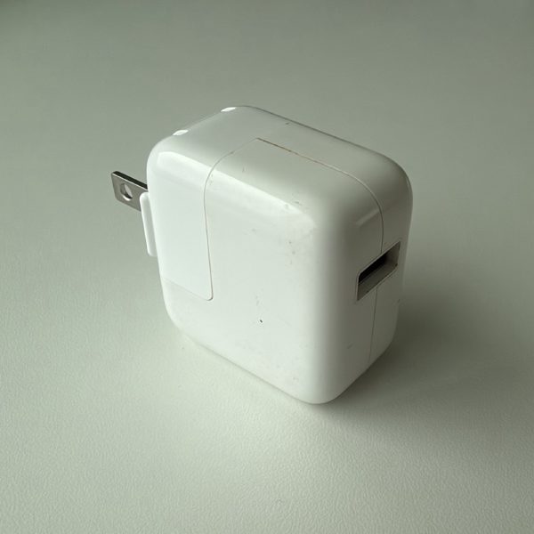 Apple 10W USB Power Adapter, model A1357, with a single USB-A port and a folding prong.